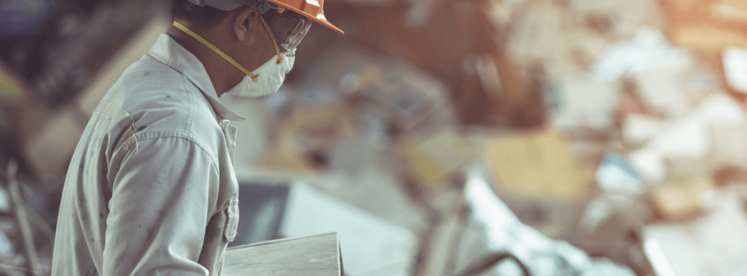 Man in full PPE sorting through e-waste and WEEE at a recycling facility